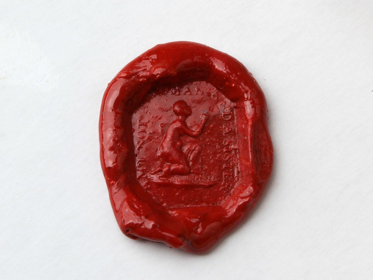 Red wax seal created using a seal shaped like an octagon with a figure of a woman carved into it. The figure is kneeling, looking up towards the right with her hands clasped. She has very short hair and a tunic wrapped around her waist. The words AM I NOT A WOMAN AND A SISTER are around the edge of the seal. 
